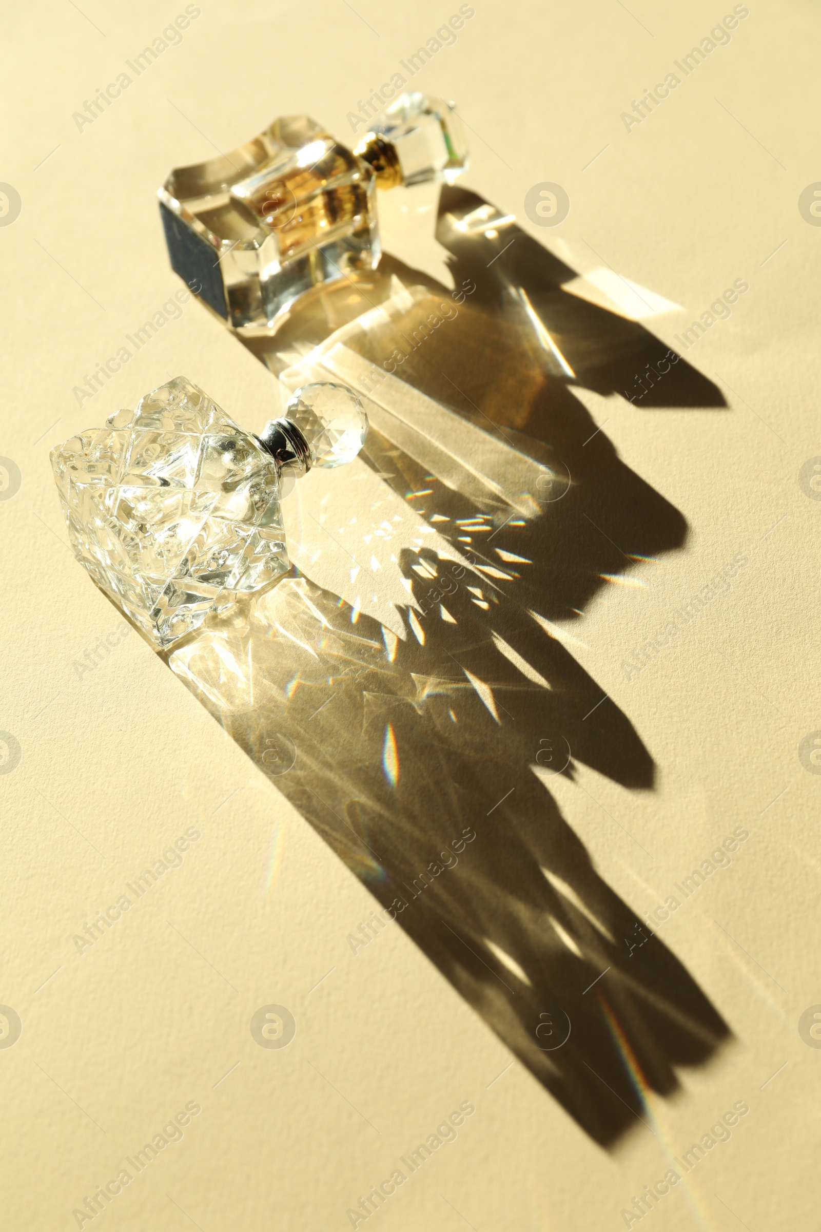 Photo of Perfume bottles casting beautiful shadows on beige background