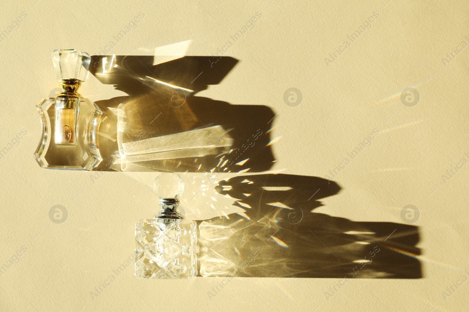 Photo of Perfume bottles casting beautiful shadows on beige background, flat lay