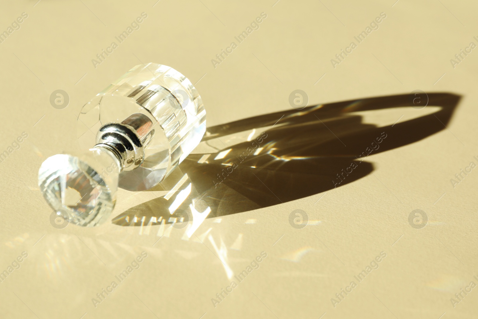 Photo of One perfume bottle casting beautiful shadow on beige background, closeup. Space for text