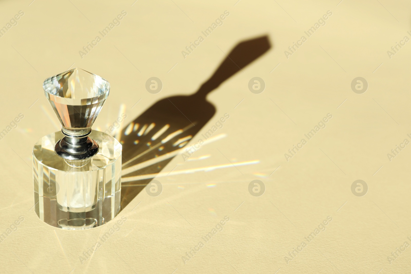 Photo of One perfume bottle casting beautiful shadow on beige background, closeup. Space for text