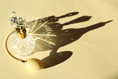 Photo of Perfume bottles casting beautiful shadows on beige background, closeup. Space for text