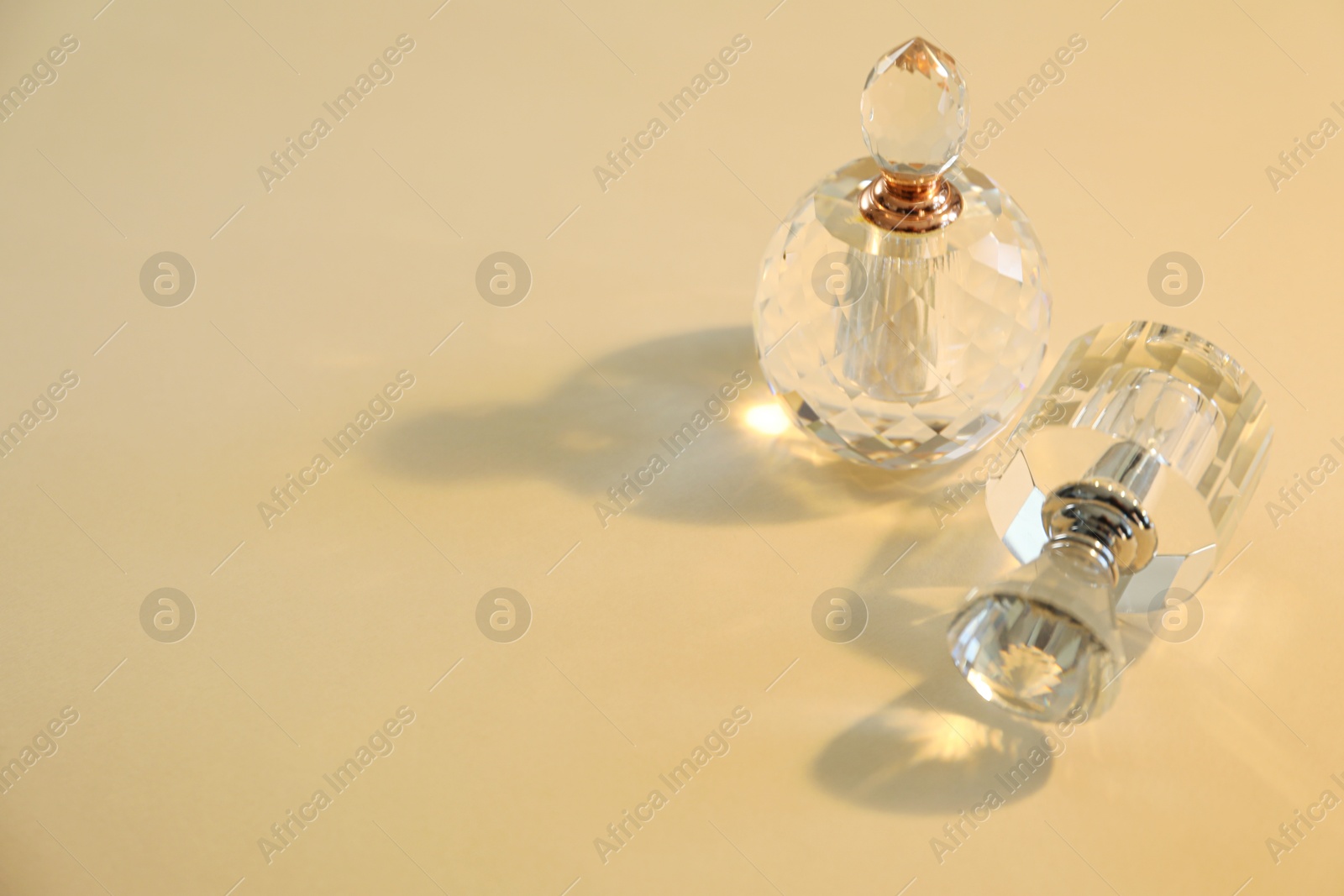 Photo of Perfume bottles casting beautiful shadows on beige background. Space for text