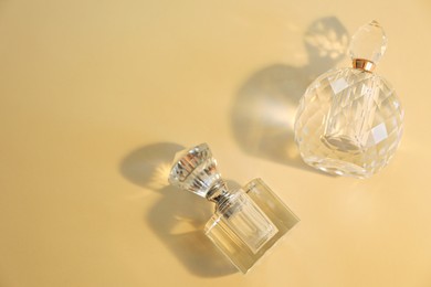 Perfume bottles casting beautiful shadows on beige background, flat lay. Space for text