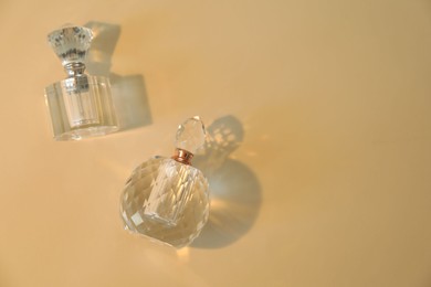 Photo of Perfume bottles casting beautiful shadows on beige background, flat lay. Space for text