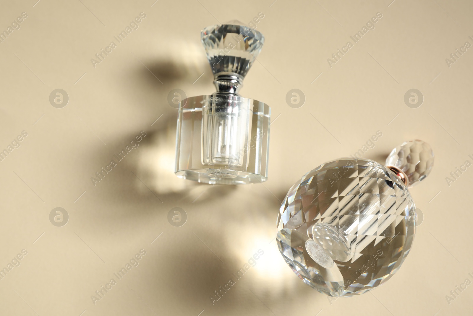 Photo of Perfume bottles casting beautiful shadows on beige background, flat lay. Space for text