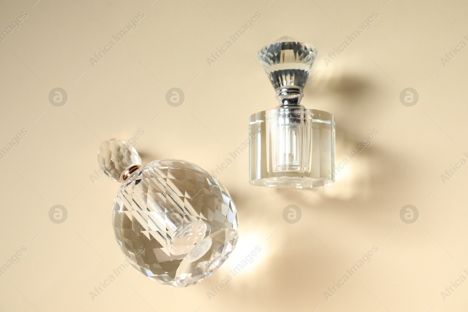 Photo of Perfume bottles casting beautiful shadows on beige background, flat lay