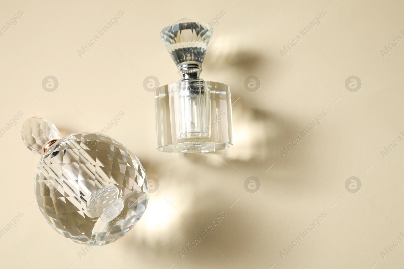 Photo of Perfume bottles casting beautiful shadows on beige background, flat lay. Space for text