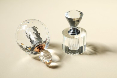 Photo of Perfume bottles casting beautiful shadows on beige background, closeup