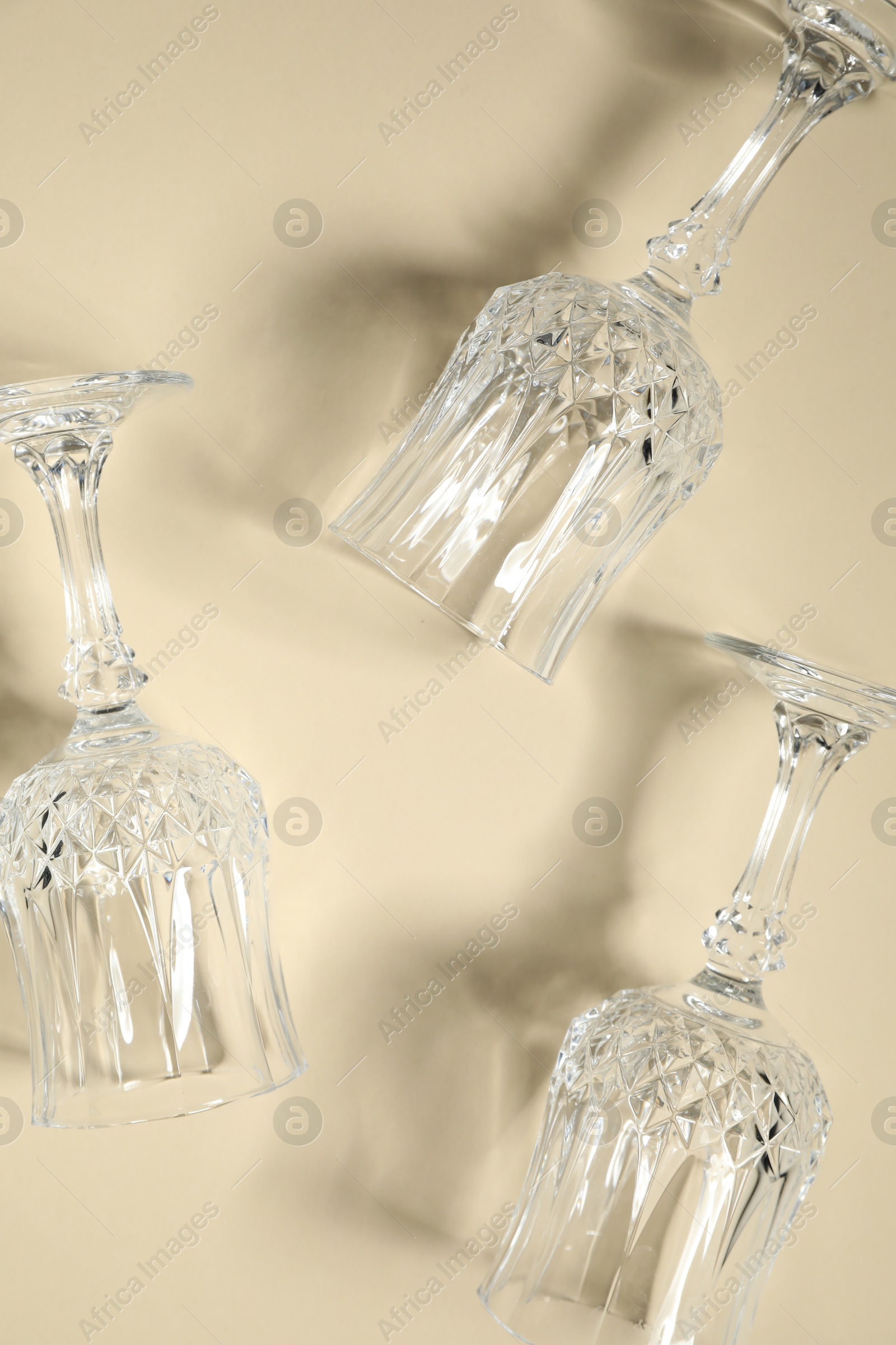 Photo of Empty wine glasses casting beautiful shadows on beige background, flat lay