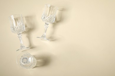 Photo of Empty wine glasses casting beautiful shadows on beige background, flat lay. Space for text