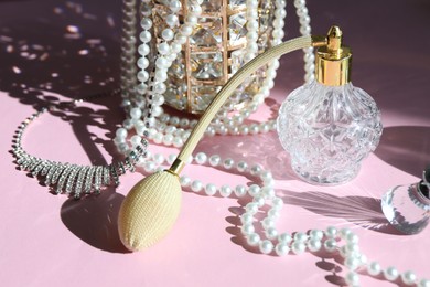 Photo of Bottle of perfume and stylish jewelry on pink background with shadows