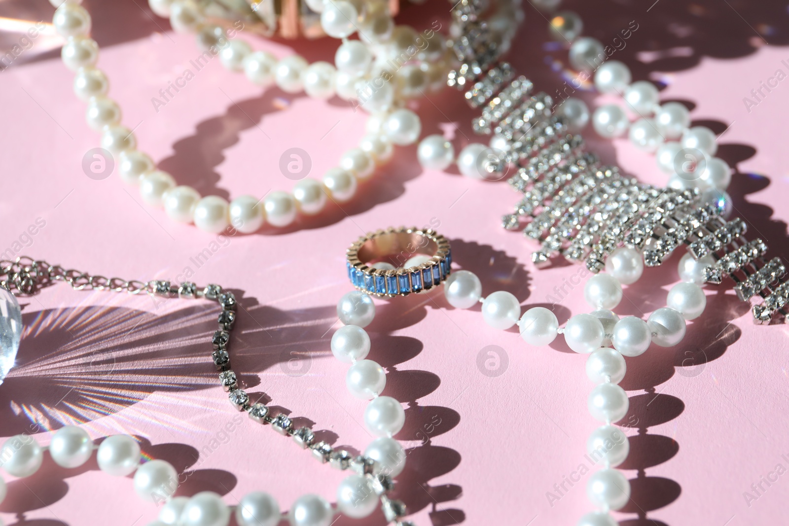 Photo of Many stylish jewelry on pink background, closeup