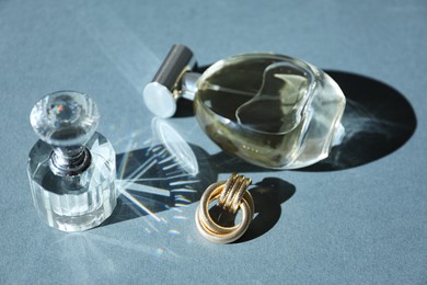 Photo of Perfume bottles and stylish earring on grey background