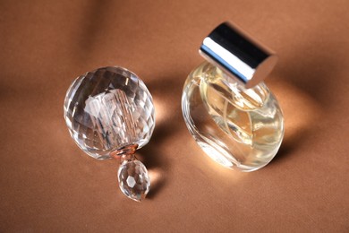 Photo of Bottles of fragrant perfume on brown background