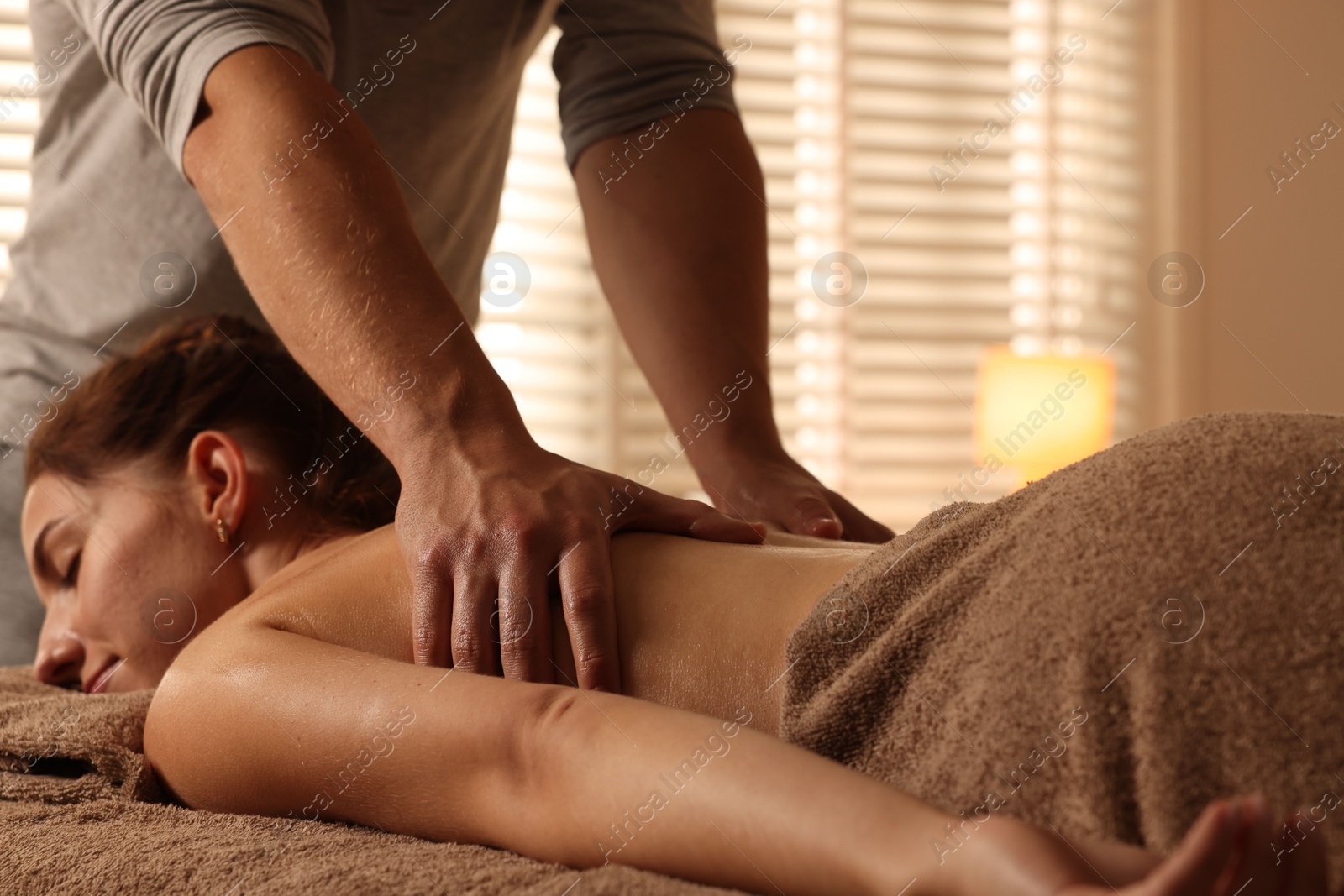 Photo of Osteopath massaging woman's back on couch indoors, closeup. Manual therapy