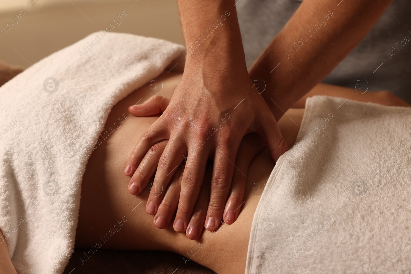 Photo of Osteopath massaging woman's belly indoors, closeup. Manual therapy