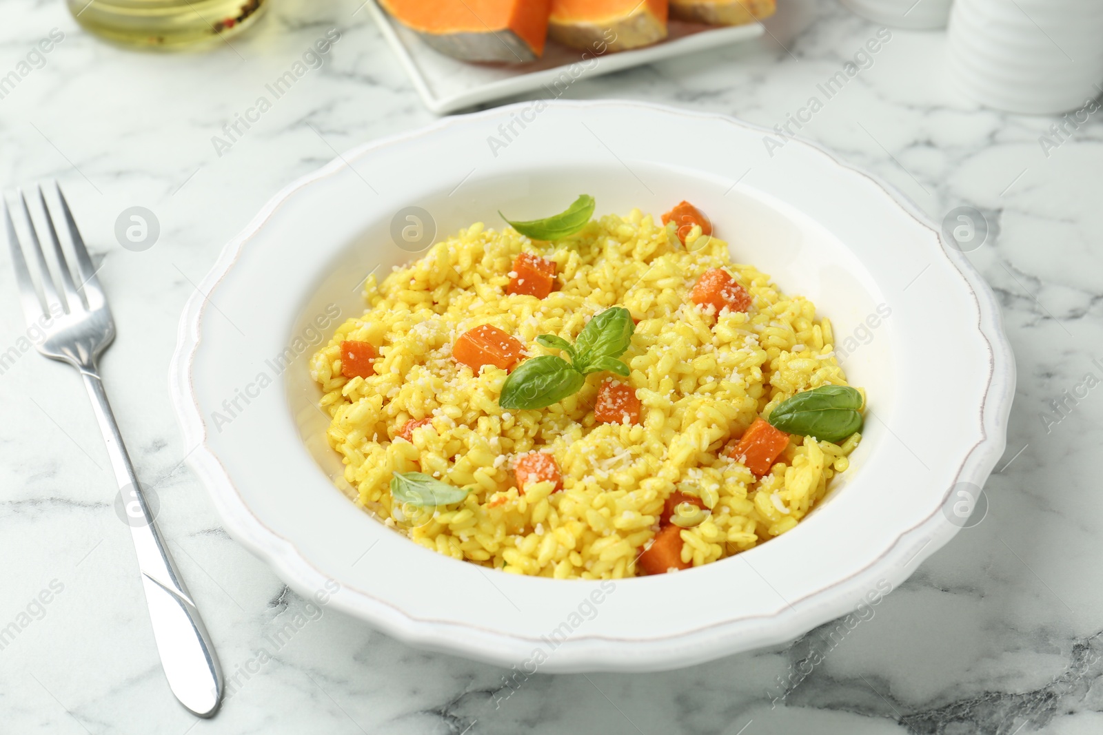 Photo of Delicious pumpkin risotto served on white marble table, closeup