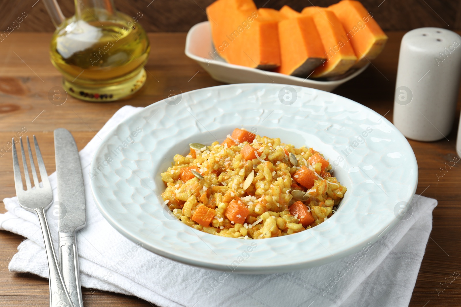 Photo of Delicious pumpkin risotto served on wooden table