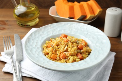 Photo of Delicious pumpkin risotto served on wooden table