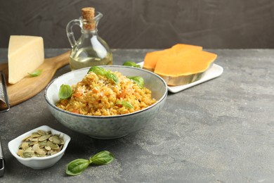 Photo of Delicious pumpkin risotto with basil on grey table