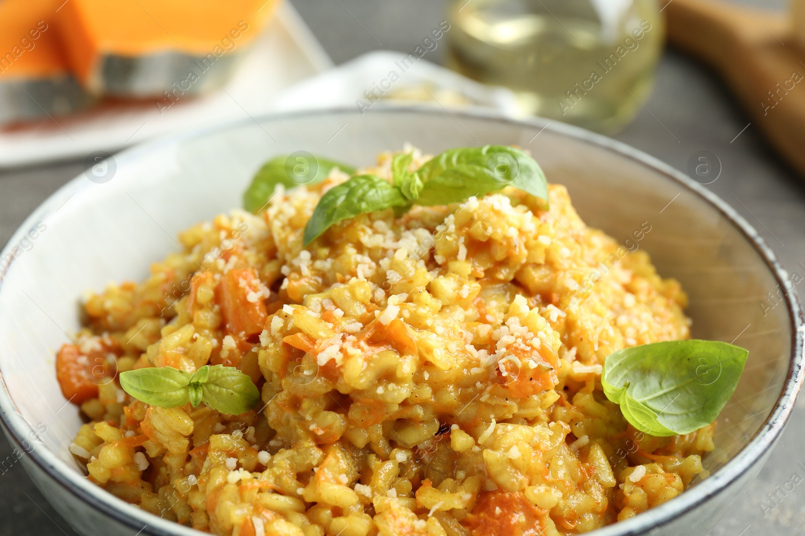 Photo of Delicious pumpkin risotto with basil on table, closeup