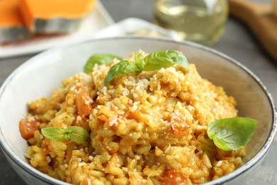 Photo of Delicious pumpkin risotto with basil on table, closeup