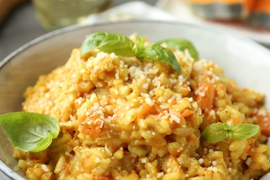 Photo of Delicious pumpkin risotto with basil on table, closeup