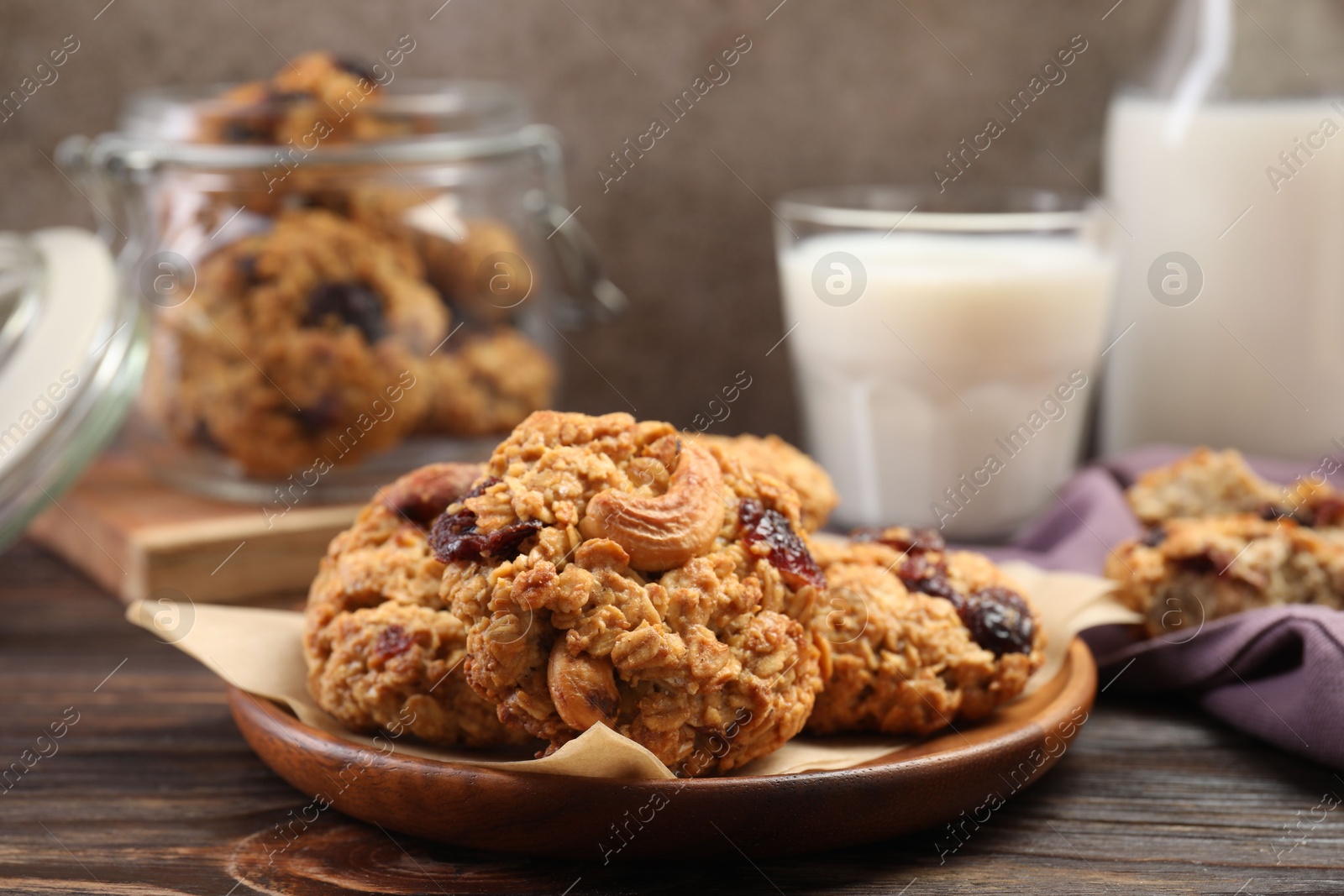 Photo of Delicious oatmeal cookies with raisins and nuts served on wooden table, closeup