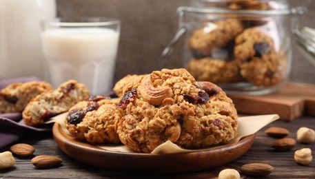 Photo of Delicious oatmeal cookies with raisins and nuts served on wooden table, closeup