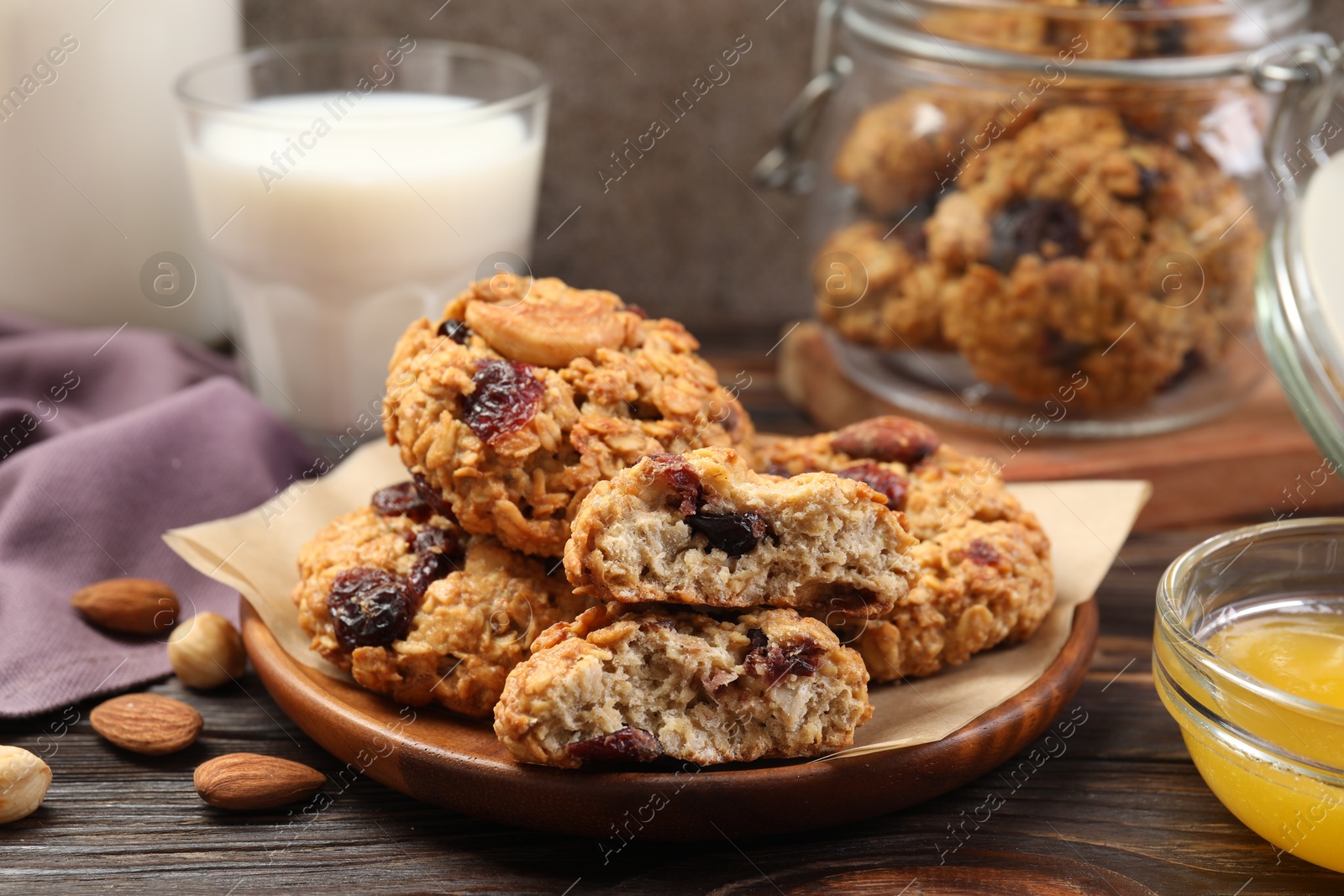 Photo of Delicious oatmeal cookies with raisins and nuts served on wooden table, closeup