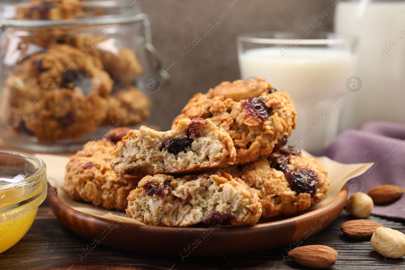 Photo of Delicious oatmeal cookies with raisins and nuts served on wooden table, closeup