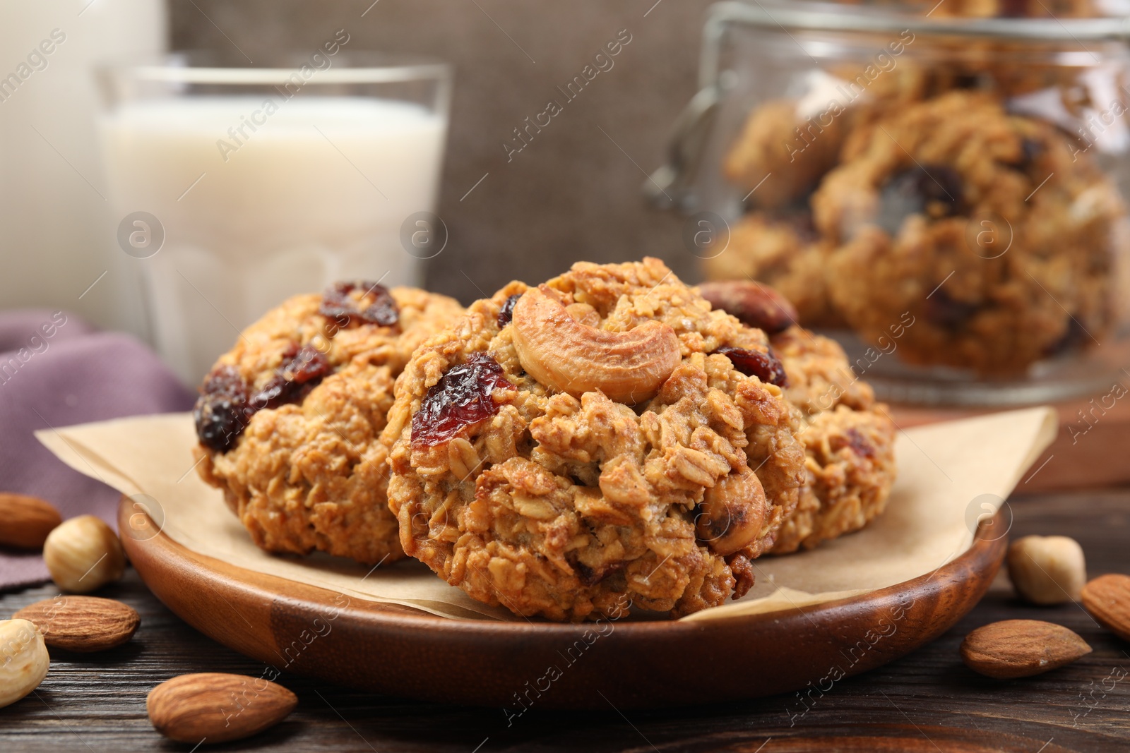 Photo of Delicious oatmeal cookies with raisins and nuts served on wooden table, closeup