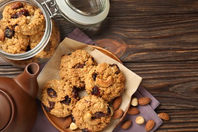 Photo of Delicious oatmeal cookies with raisins and nuts served on wooden table, flat lay. Space for text