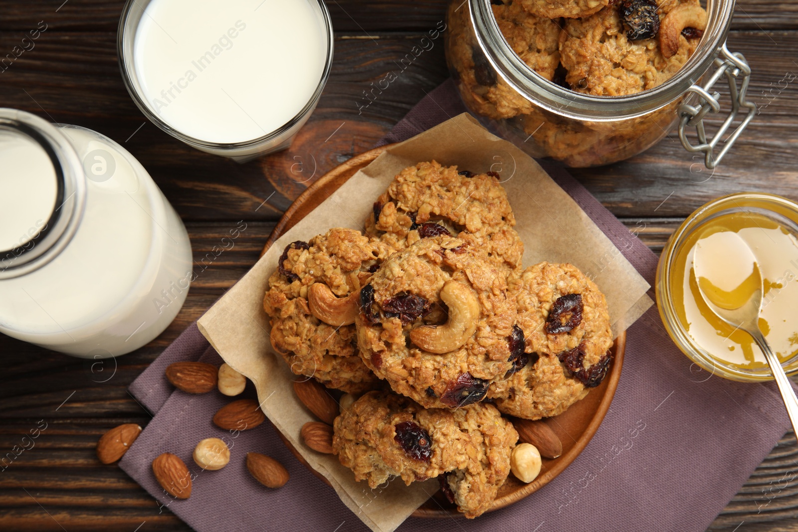 Photo of Delicious oatmeal cookies with raisins and nuts served on wooden table, flat lay