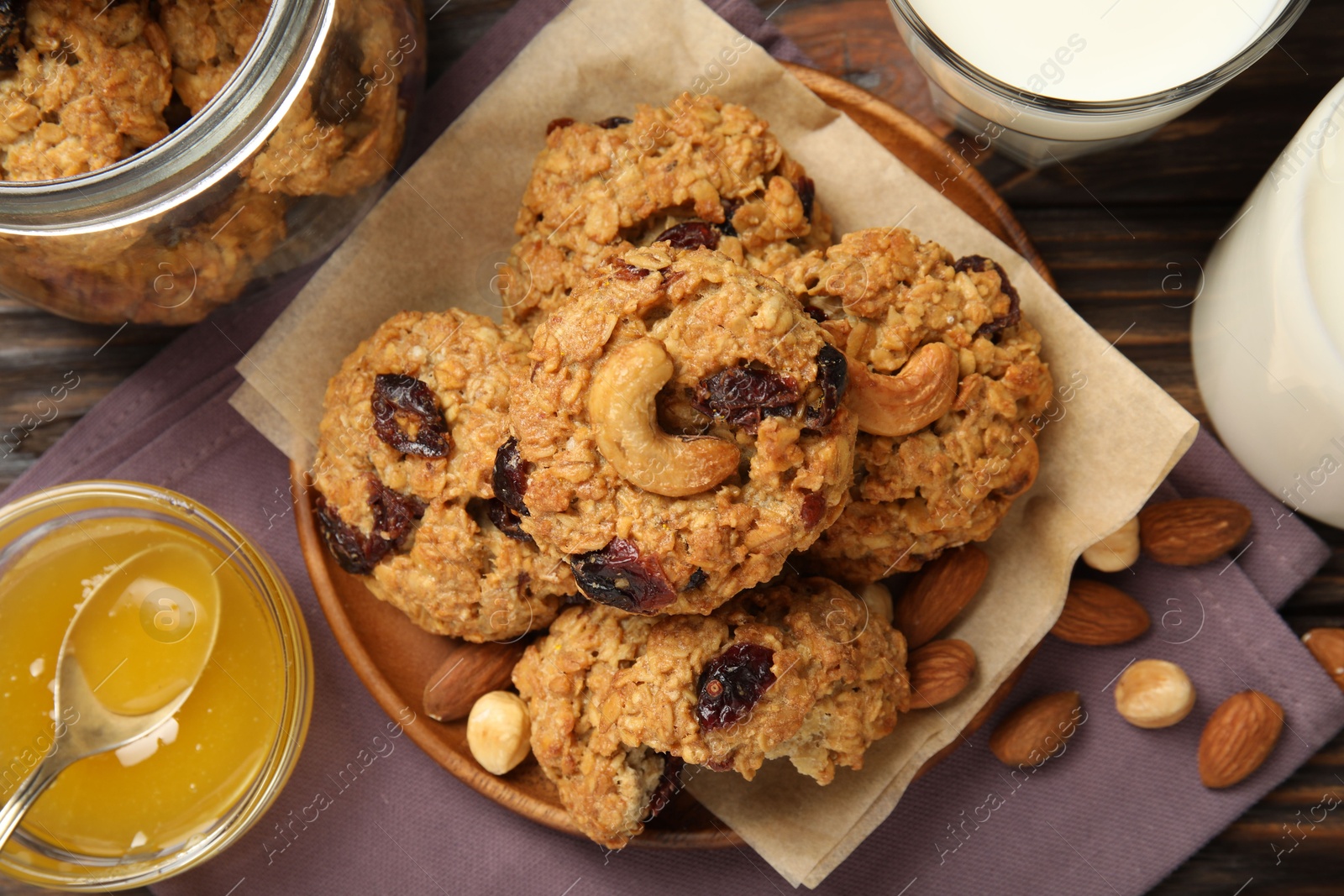 Photo of Delicious oatmeal cookies with raisins and nuts served on wooden table, flat lay