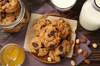 Photo of Delicious oatmeal cookies with raisins and nuts served on wooden table, flat lay