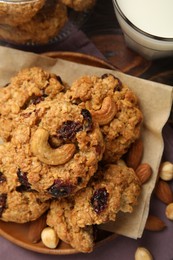 Photo of Delicious oatmeal cookies with raisins and nuts served on wooden table, flat lay