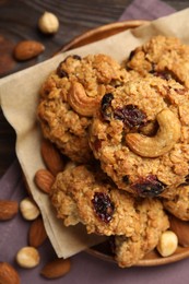 Delicious oatmeal cookies with raisins and nuts on wooden table, flat lay