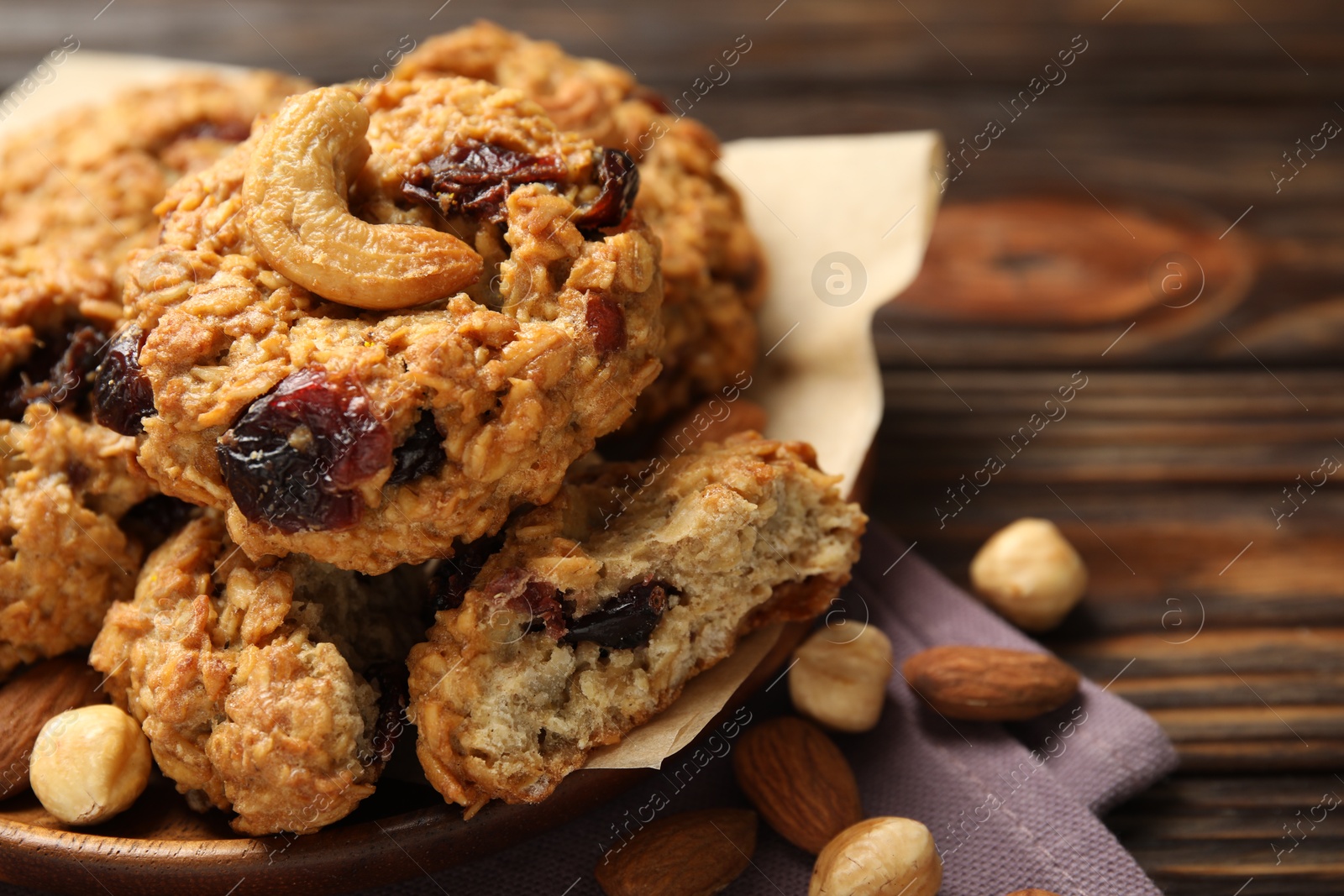 Photo of Delicious oatmeal cookies with raisins and nuts on wooden table, closeup