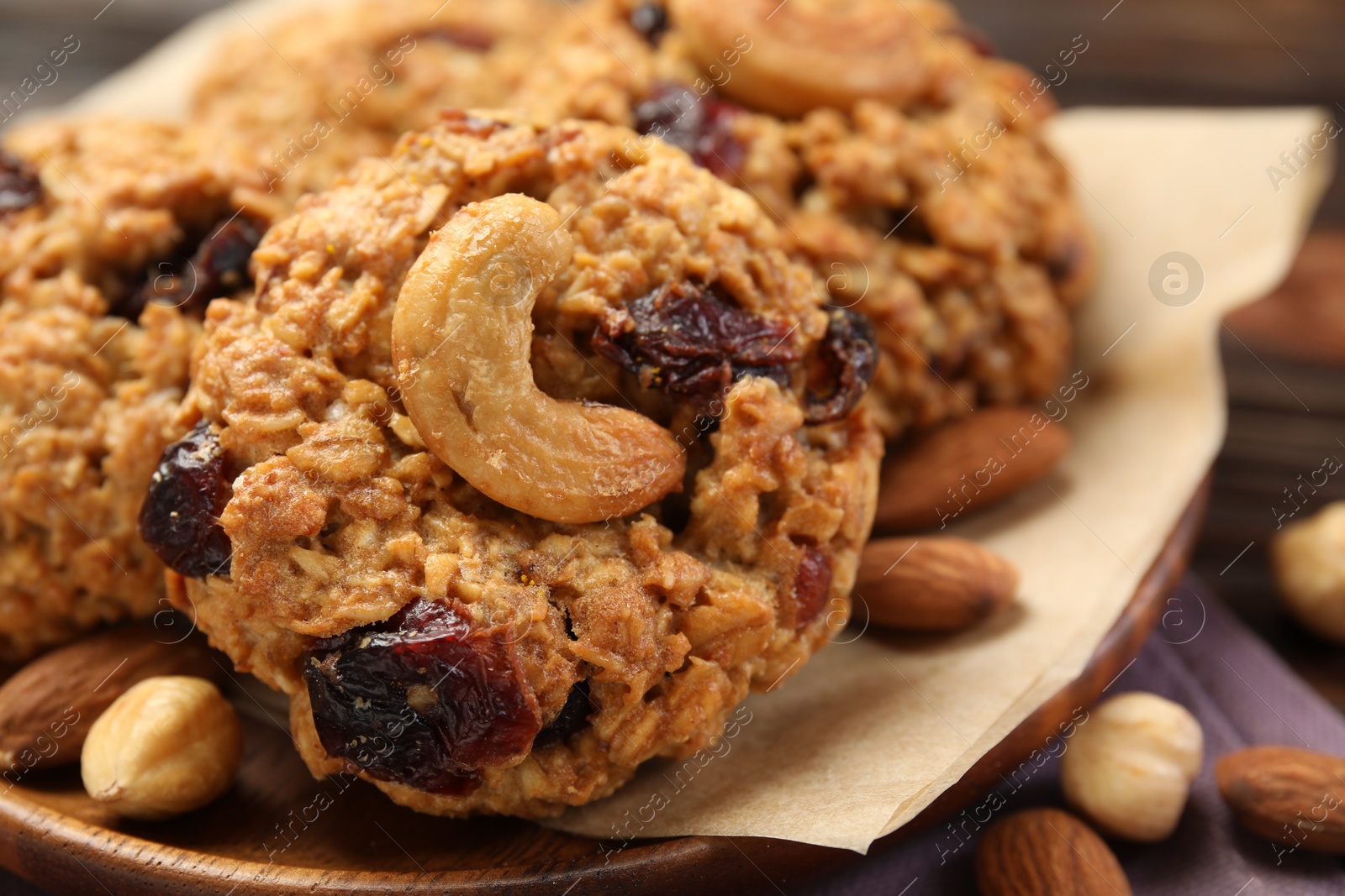 Photo of Delicious oatmeal cookies with raisins and nuts on wooden table, closeup