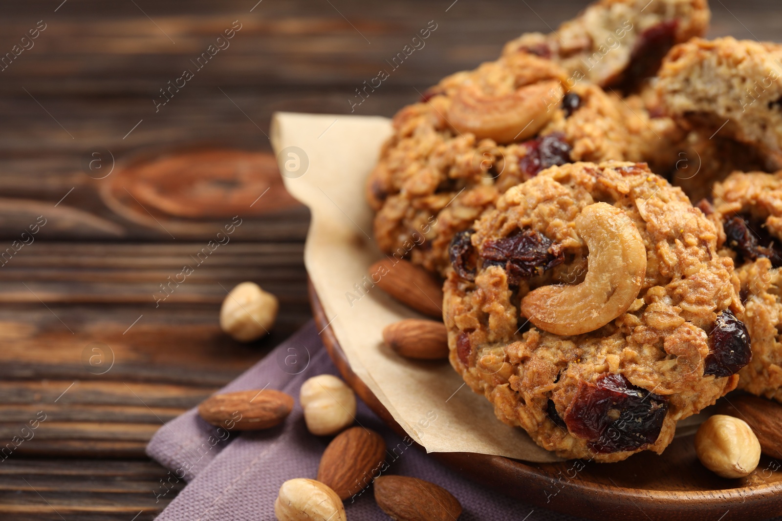 Photo of Delicious oatmeal cookies with raisins and nuts on wooden table, closeup