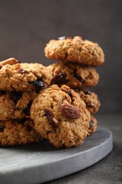 Delicious oatmeal cookies with raisins and nuts on grey table, closeup