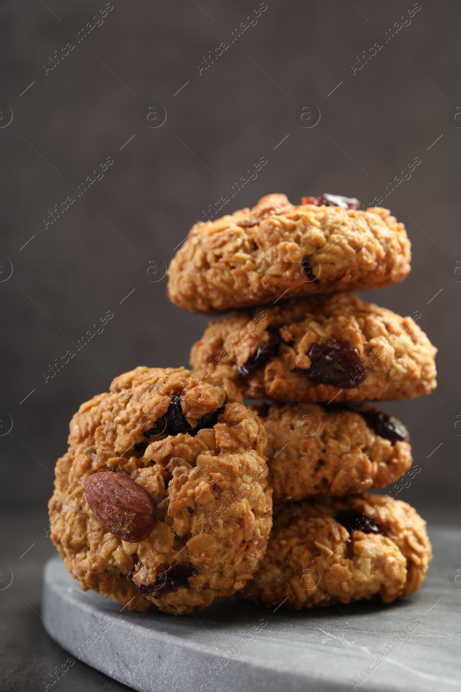 Photo of Delicious oatmeal cookies with raisins and nuts on grey table, closeup