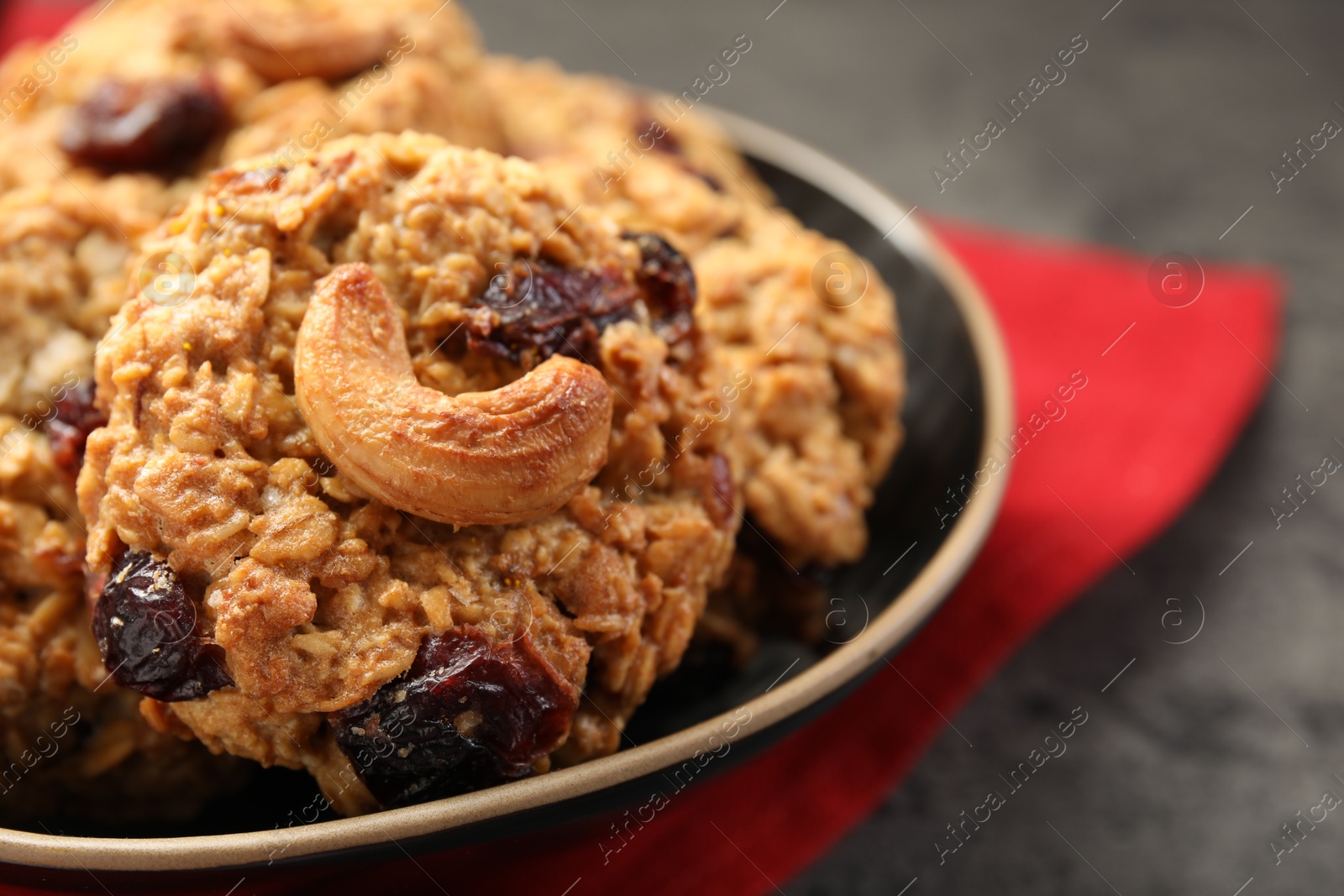 Photo of Delicious oatmeal cookies with raisins and nuts on grey table, closeup