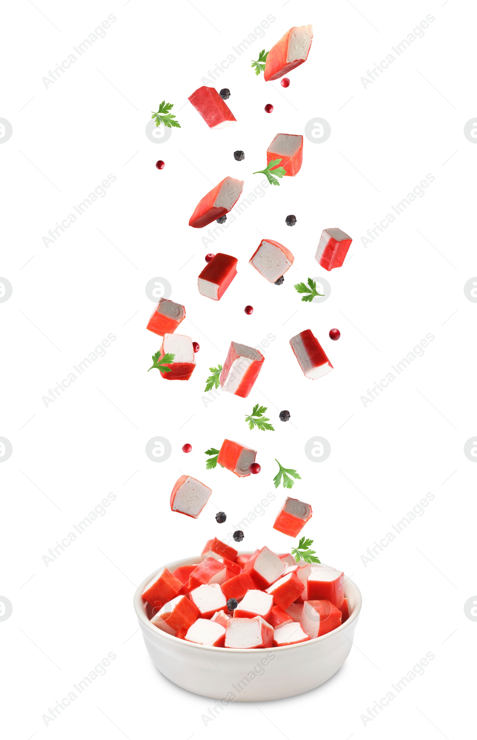 Image of Crab stick pieces, parsley and mix of peppers falling into bowl on white background