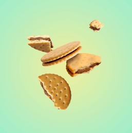 Image of Tasty broken sandwich cookies in air on turquoise gradient background