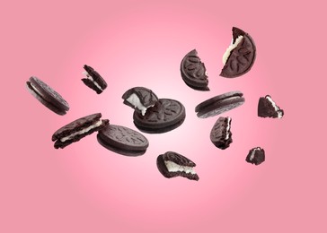 Image of Tasty broken sandwich cookies in air on pink background