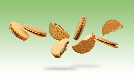 Image of Tasty broken sandwich cookies in air on green gradient background