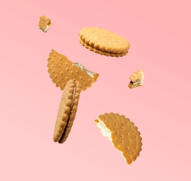 Image of Tasty broken sandwich cookies in air on pink background