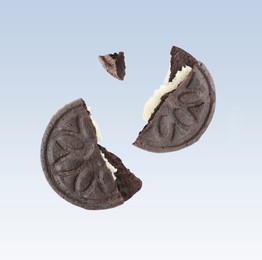 Image of Tasty broken sandwich cookie in air on light blue gradient background